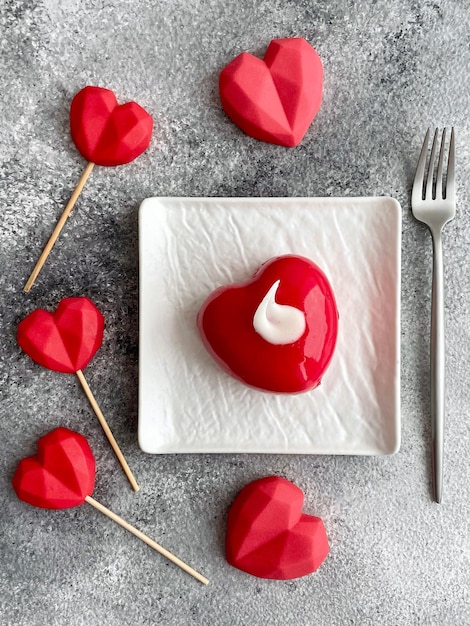 Deliziosa torta rossa dolce fresca con ripieno di formaggio a forma di cuore con caramelle su un bastone Sfondo per la festa di San Valentino