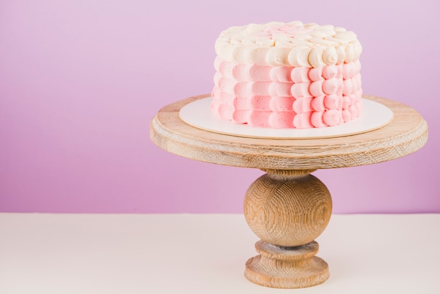 Deliziosa torta sul cesto di legno davanti alla parete rosa