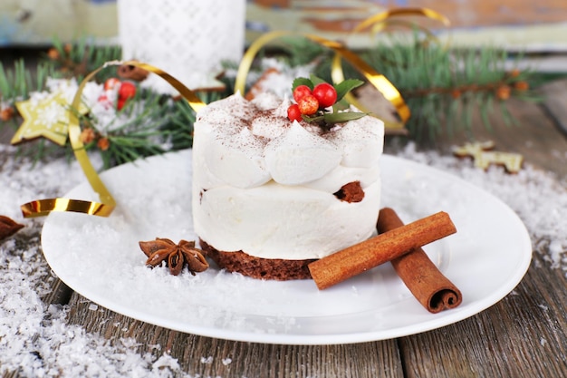 Deliziosa torta sul piatto con cannella e anice stellato su sfondo di decorazioni natalizie