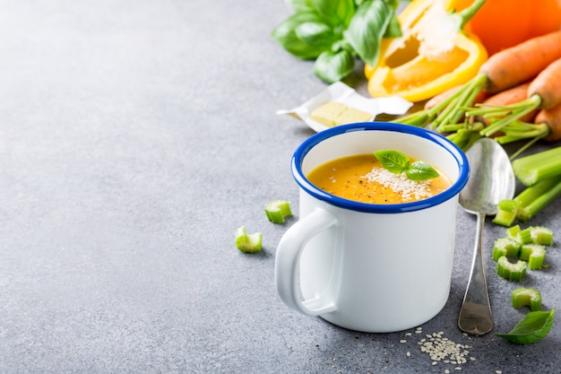 Deliziosa zuppa di carote fatta in casa con semi di sesamo di carne in tazza di smalto.