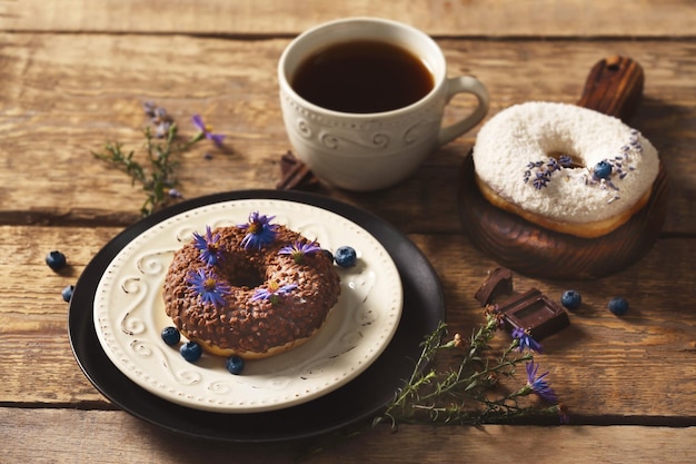 Deliziose ciambelle al cioccolato e tazza di caffè sul primo piano della tavola di legno