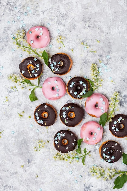 Deliziose ciambelle glassate su sfondo bianco e fiori