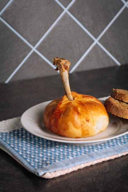 Deliziose cosce di pollo cotte in un impasto su un piatto bianco sullo sfondo scuro