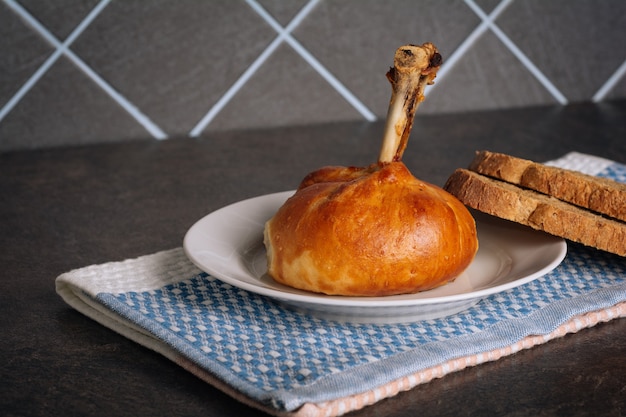 Deliziose cosce di pollo cotte in un impasto su un piatto bianco sullo sfondo scuro