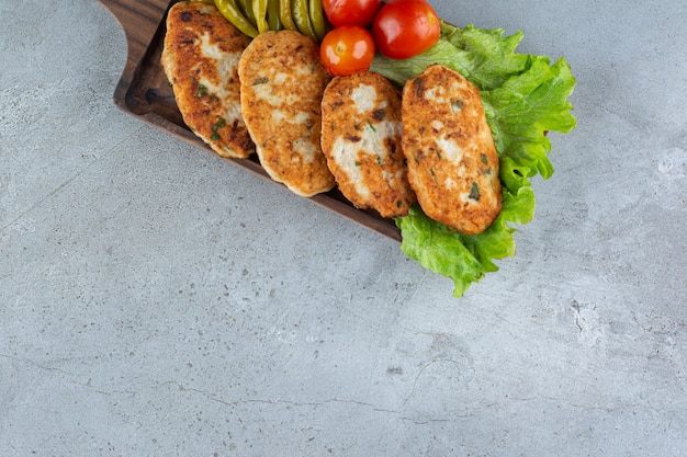 Deliziose cotolette di pollo con verdure poste sul tavolo di pietra.