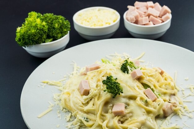 Deliziose Fettuccine con besciamella, broccoli, dadini di petto di tacchino e formaggio grattugiato. Messa a fuoco selettiva.