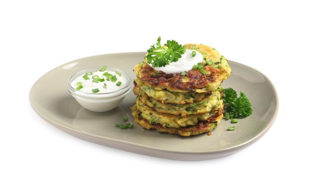 Deliziose frittelle di zucchine con panna acida su sfondo bianco