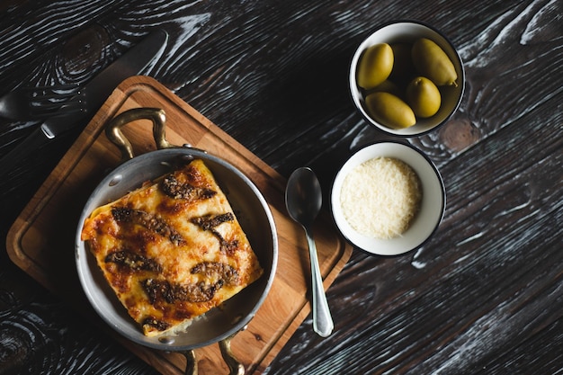 Deliziose lasagne con olive grandi su fondo scuro. Fotografia di cibo