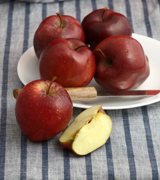 Deliziose mele in piatto con un coltello su una tovaglia a righe