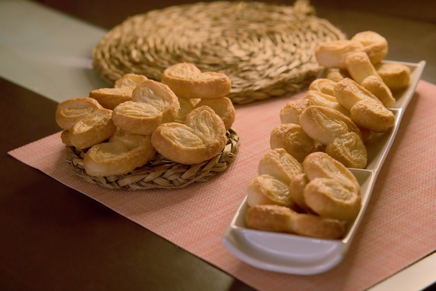 Deliziose palme di pasta sfoglia su piatto rettangolare bianco e piatto di vimini