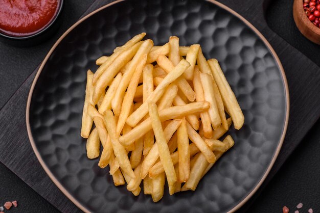 Deliziose patatine fritte croccanti con sale e spezie su uno sfondo di cemento scuro