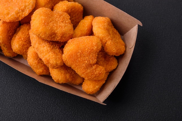 Deliziose pepite di pollo croccanti fresche su uno sfondo di cemento scuro