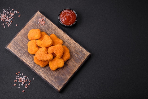 Deliziose pepite di pollo croccanti fresche su uno sfondo di cemento scuro