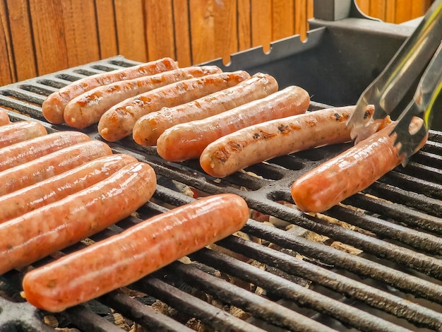 Deliziose salsicce tedesche che sfrigolano sui carboni al barbecue grillman che cucina carne sulla griglia del barbecue