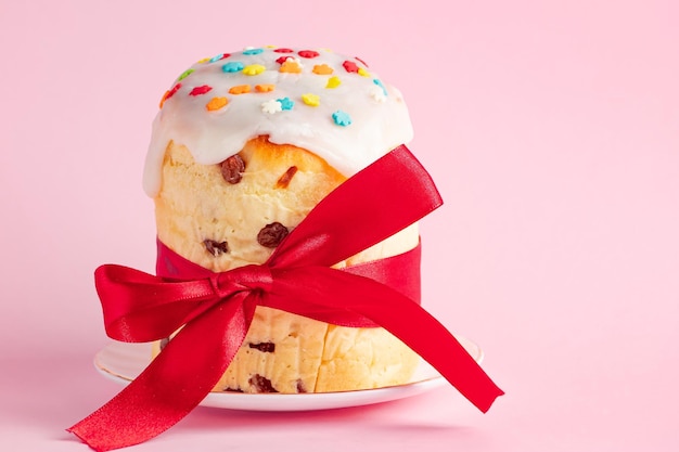 Deliziose torte pasquali panettone decorato con nastro e fiori su sfondo rosa Cibo festivo