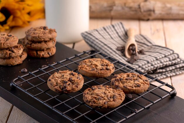 Deliziosi biscotti al cioccolato su una cremagliera nera con una bottiglia di latte