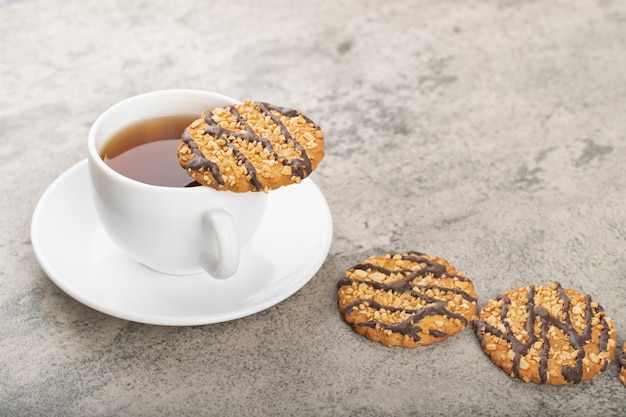 Deliziosi biscotti di farina d'avena glassati con tazza di tè su pietra.