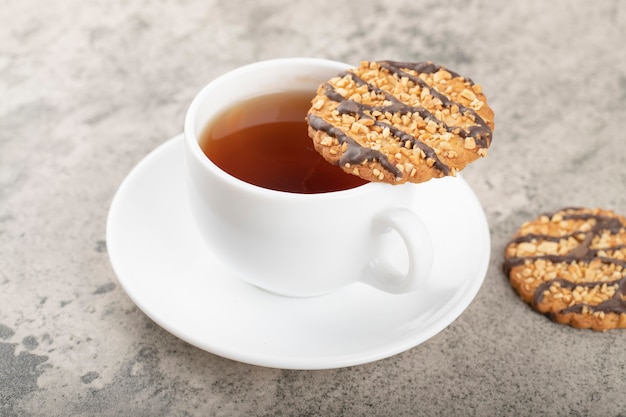 Deliziosi biscotti di farina d'avena glassati con tazza di tè su pietra.