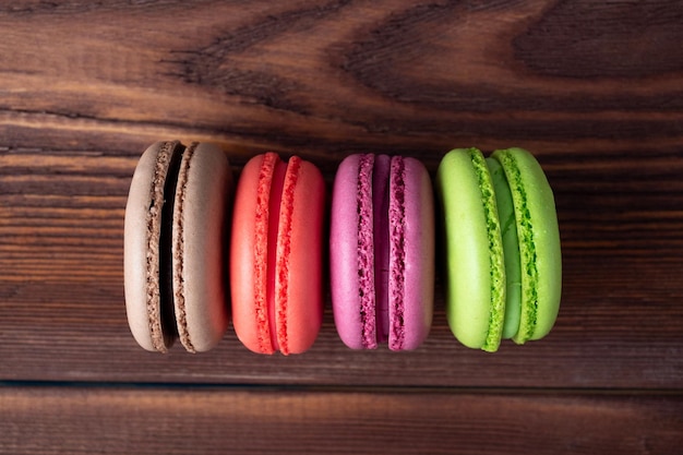 Deliziosi biscotti di mandorle dolci di diversi colori su uno sfondo di legno marrone. Vista dall'alto, posizione piatta