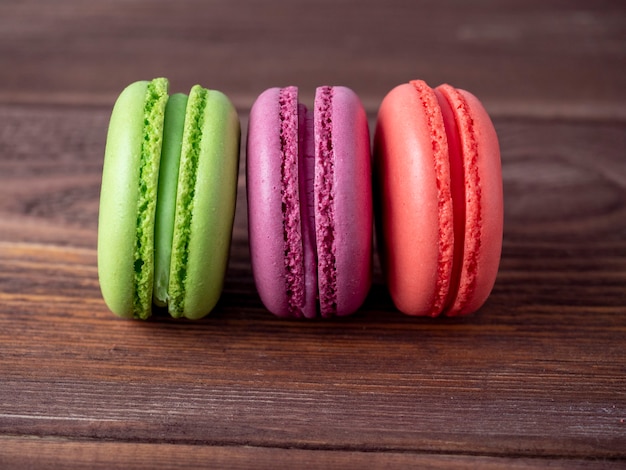 Deliziosi biscotti di mandorle dolci di diversi colori su uno sfondo di legno marrone. Vista laterale