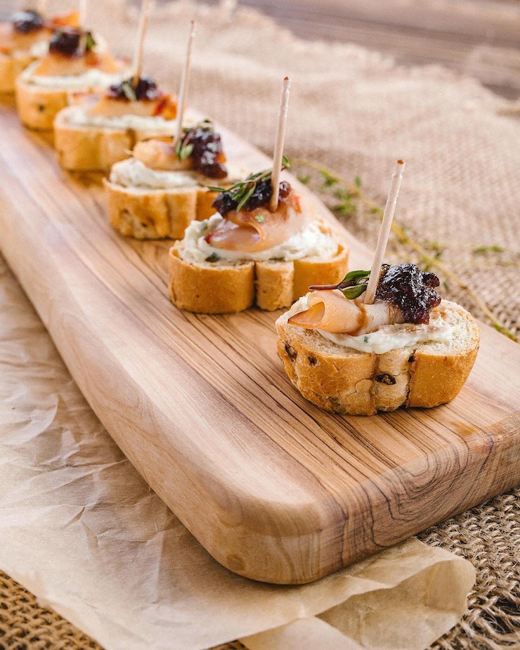 Foto deliziosi canapè gourmet con formaggio e condimenti su una tavola di legno