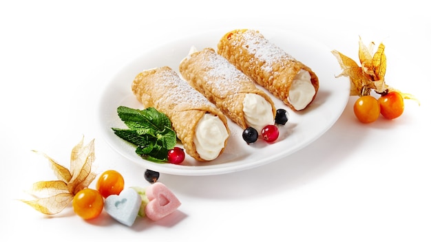 Deliziosi cannoli dolci con frutti di bosco su uno sfondo bianco isolato.