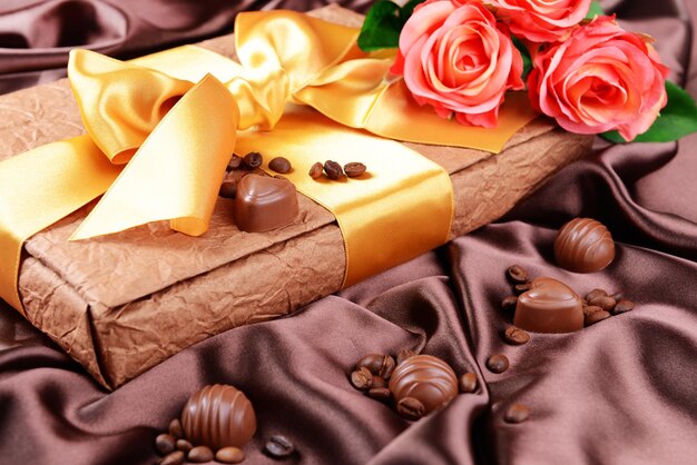 Deliziosi cioccolatini in scatola con fiori su sfondo marrone