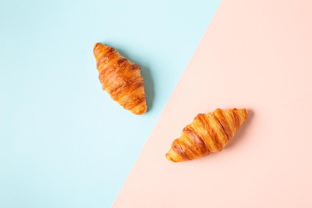 Deliziosi croissant freschi su sfondo pastello, vista dall'alto.