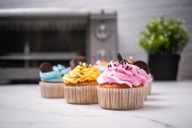 Deliziosi cupcakes fatti in casa con crema colorata e guarnire con caramelle e biscotti al cioccolato.