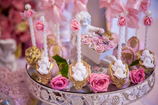 Deliziosi dessert al wedding candy bar nell'area buffet: cake pops decorati con angeli e cammei e freschi boccioli di rosa.