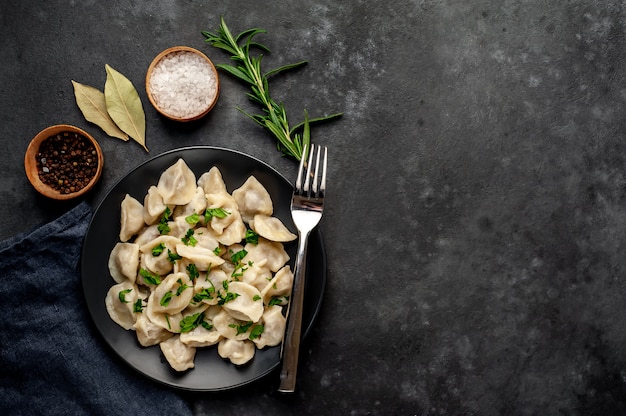 deliziosi gnocchi di farina integrale fatti in casa o gnocchi russi cosparsi di prezzemolo fresco su un piatto su un tavolo di legno, copia spazio, vista dall'alto