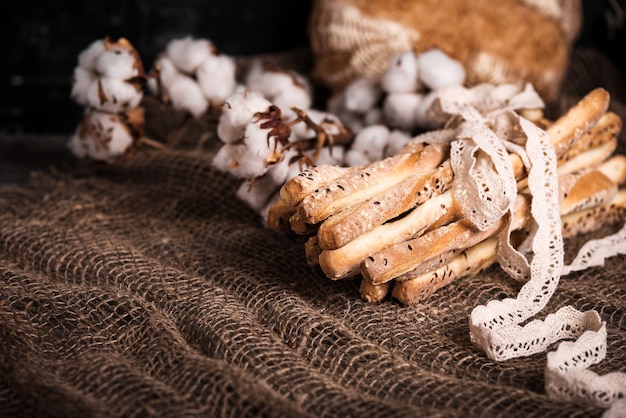 Deliziosi grissini grissini. Antipasti italiani. Tavolo in legno e fiori di tela di cotone e pizzo di lino naturale.