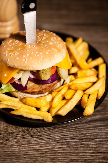 Deliziosi hamburger fatti in casa su banda nera accanto a patatine fritte. Fast food. Spuntino malsano