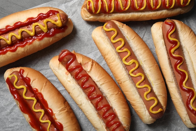 Deliziosi hot dog freschi con salse su carta pergamena piatta