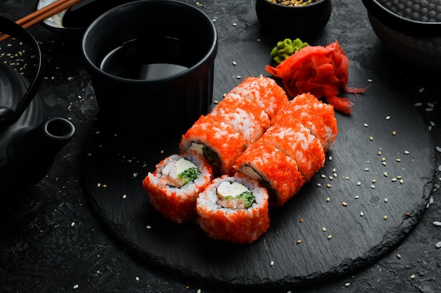 Deliziosi involtini di sushi tradizionali con caviale Cibo tradizionale giapponese su una lastra di pietra nera