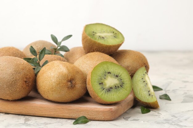 Deliziosi lotti maturi di kiwi e kiwi tagliati su una tavola su uno sfondo di cemento chiaro