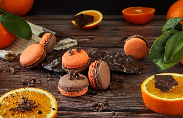 Deliziosi macaroni al sapore di cioccolato con arancione su uno sfondo di legno scuro