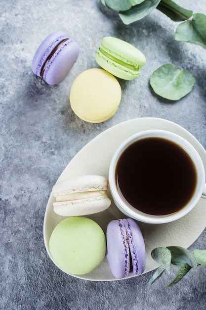 Deliziosi macarons pastello colorati con tazza di caffè e crema. Scena di pausa caffè con caramelle macaron