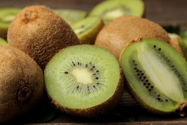 Deliziosi maturi molti kiwi e kiwi in un taglio su un tavolo di legno marrone. avvicinamento.