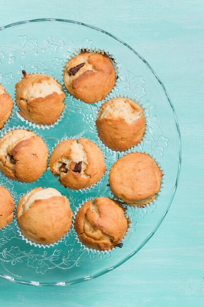 Deliziosi muffin alla vaniglia fatti in casa con cioccolato sulla lastra di vetro su sfondo turchese