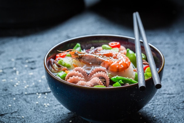 Deliziosi noodle ai frutti di mare in una ciotola scura con le bacchette