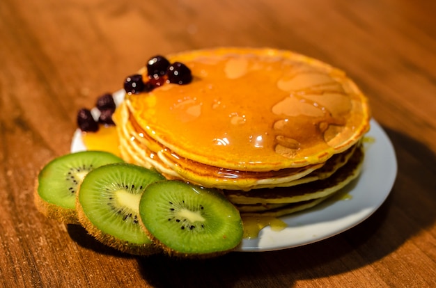 Deliziosi pancakes con miele, kiwi e frutti di bosco.