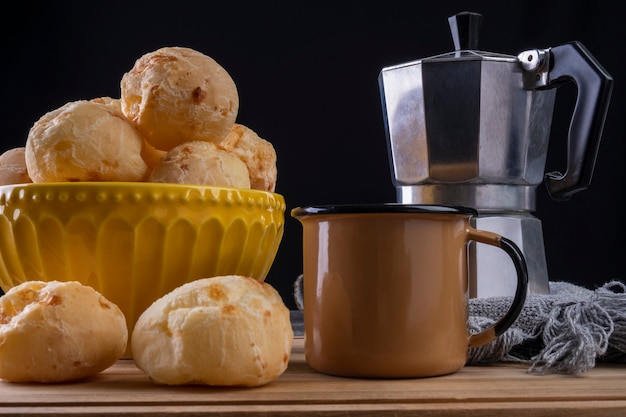 Deliziosi panini al formaggio e una tazza da caffè su sfondo scuro.