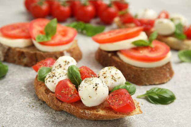 Deliziosi panini con mozzarella pomodori freschi e basilico sul tavolo grigio chiaro