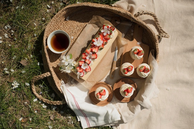 Deliziosi pasticcini a un picnic nel parco, decorati con fragole in un cesto