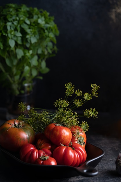 Deliziosi pomodori rossi e verdi su un tavolo scuro in un piatto. Foto di alta qualità