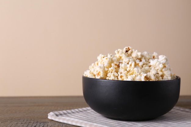 Deliziosi popcorn nella ciotola sul tavolo di legno Spazio per il testo