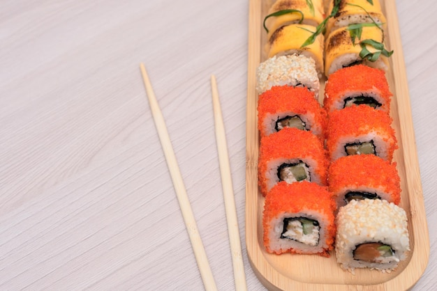 Deliziosi rotoli giapponesi con salmone avocado cetriolo formaggio su piatto di legno con bastoncini di legno con fuoco selettivo Concetto di cibo asiatico Mangiare sano