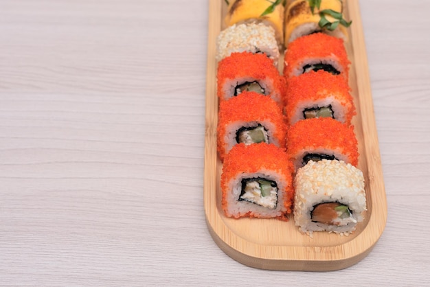 Deliziosi rotoli giapponesi con salmone avocado cetriolo formaggio su piatto di legno con messa a fuoco selettiva Concetto di cibo asiatico Mangiare sano