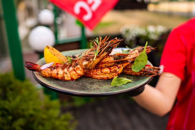 Deliziosi scampi n ristorante su un tavolo di legno, nessuna gente è visibile. Gustosi frutti di mare con vino in cafemenu.